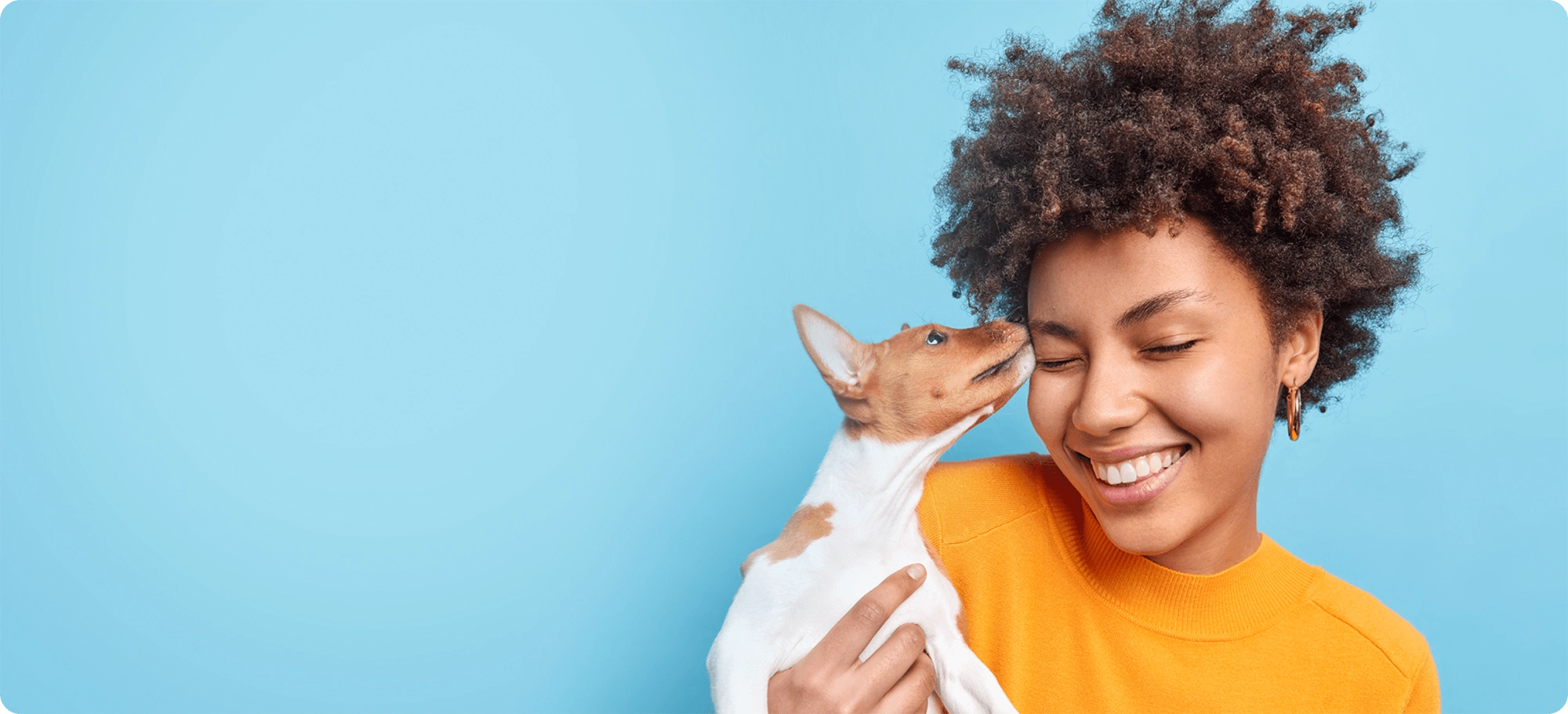 woman receiving a kiss from a small dog